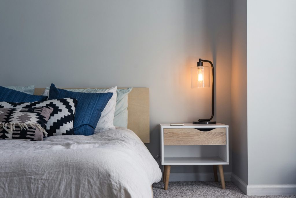 Bed and nightstand with lit lamp