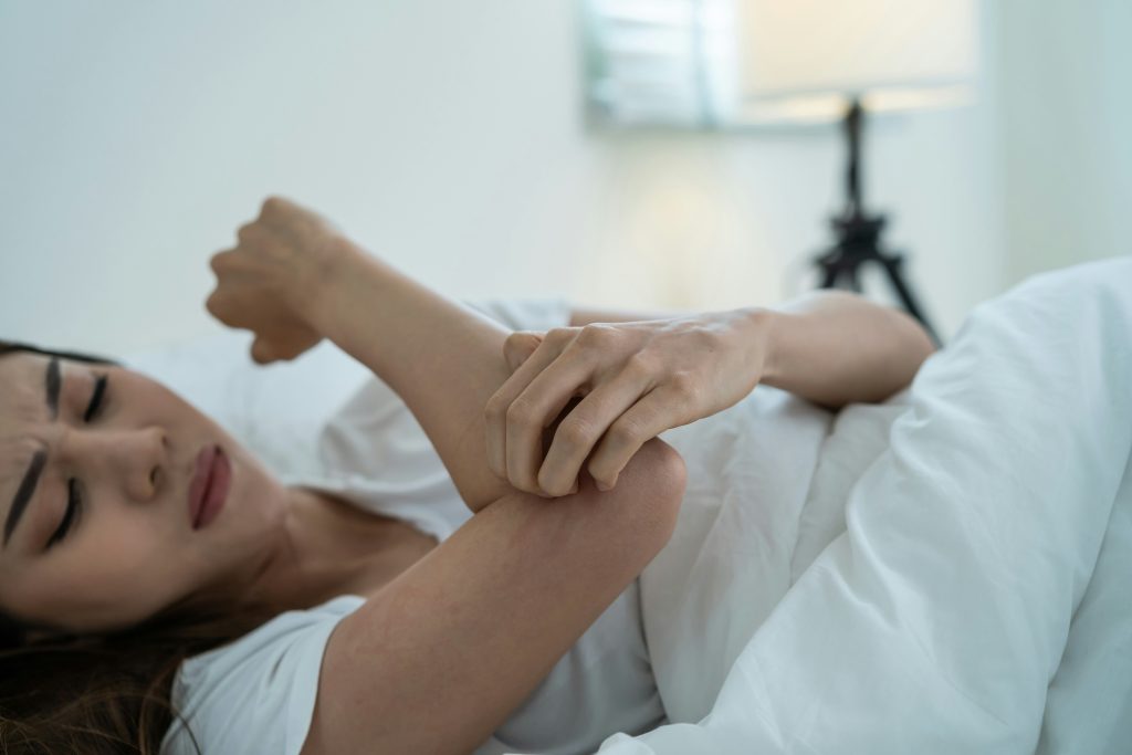 Woman lying on bed checking arm