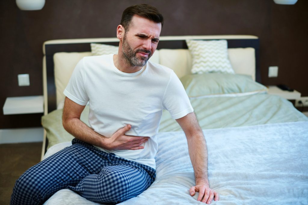 Man sitting on bed with stomach ache