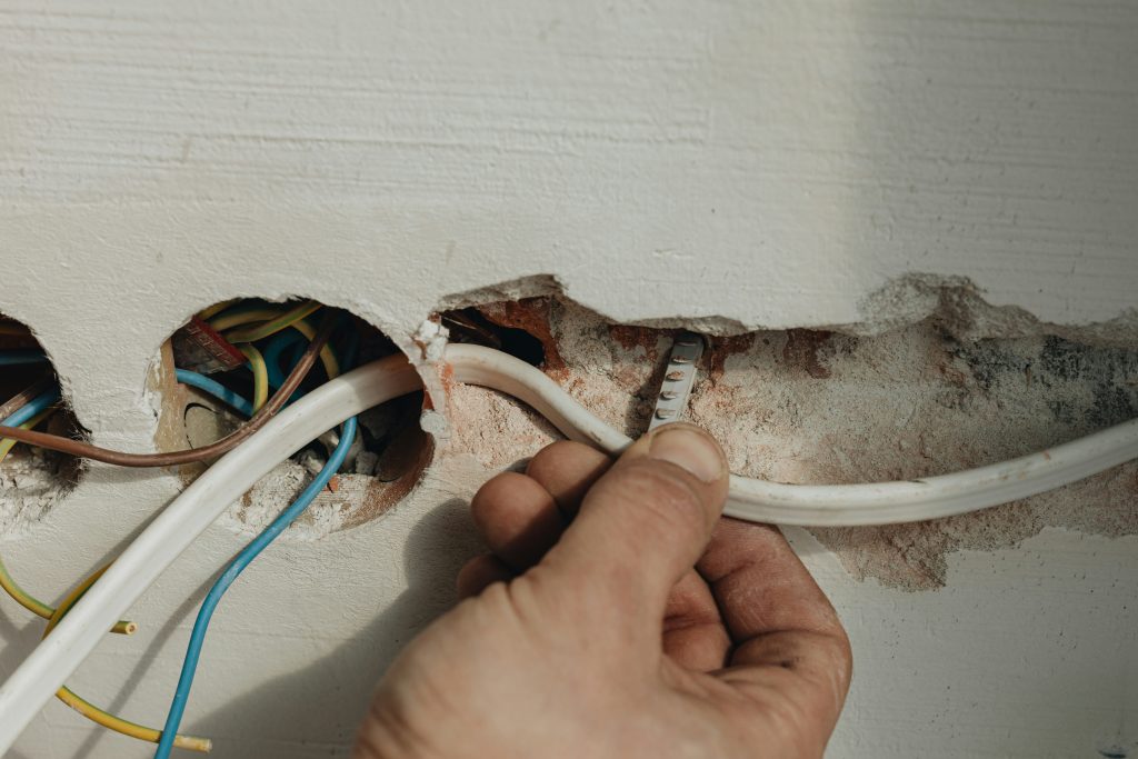 Hand pulling wires behind baseboard