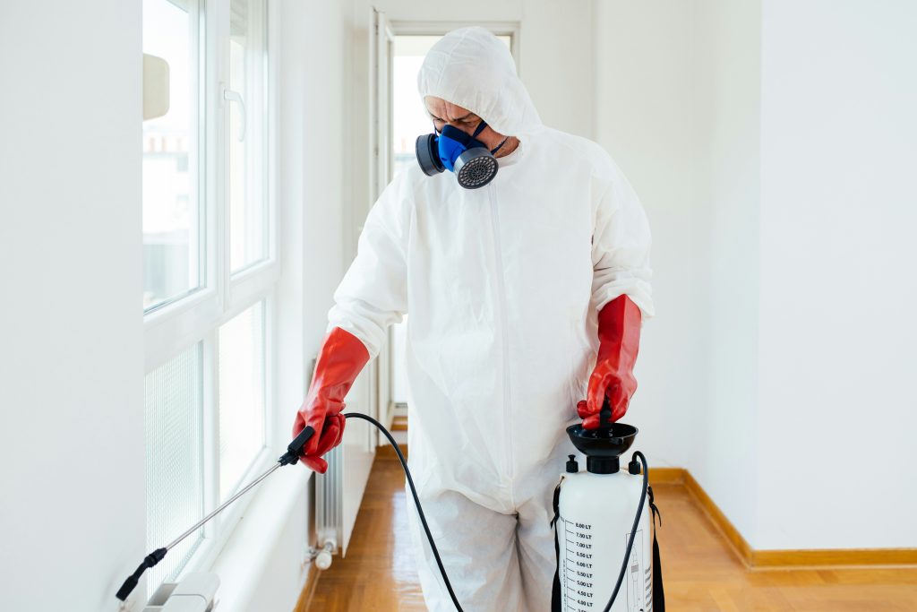 Man in protective suit spraying pesticides